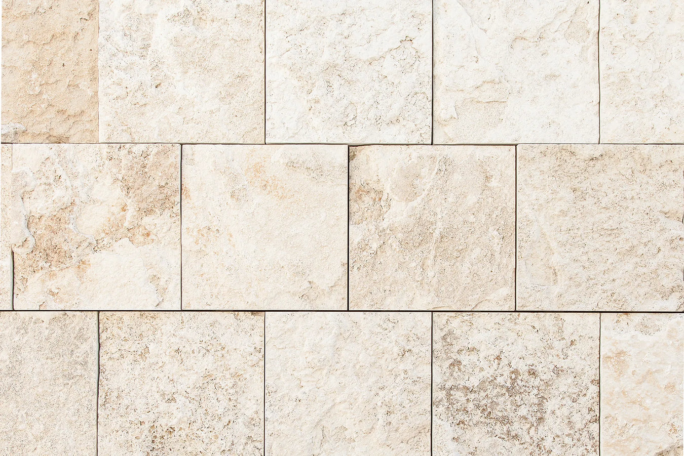 Close-up of beige natural stone tiles arranged in a staggered pattern, ideal surface for underfloor heating installations.