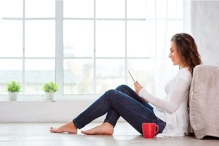 Woman enjoying underfloor heating in the living room, experiencing the comfort of heated floors.
