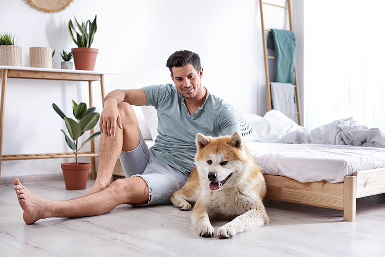 Man with dog sitting on bedroom floor enjoying electric floor heating